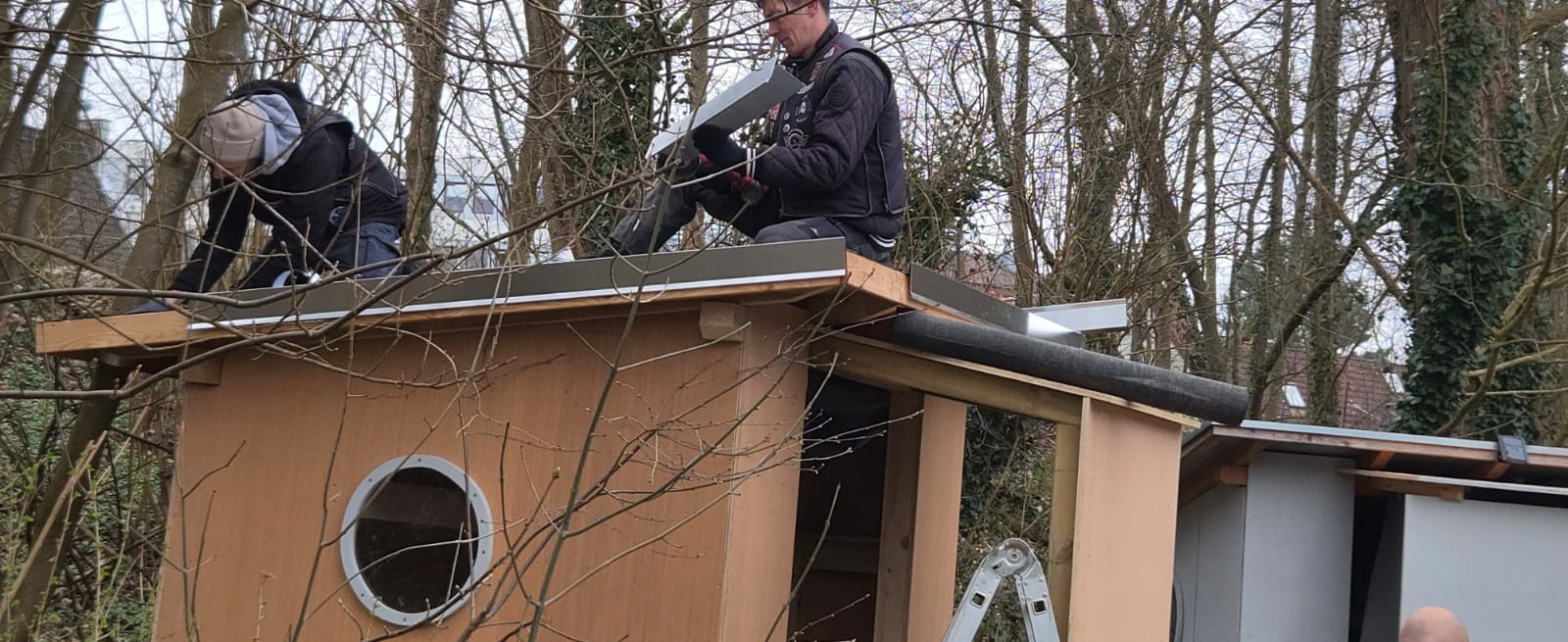 Zwei Helfer montieren die Blechabdeckung auf dem Hüttendach