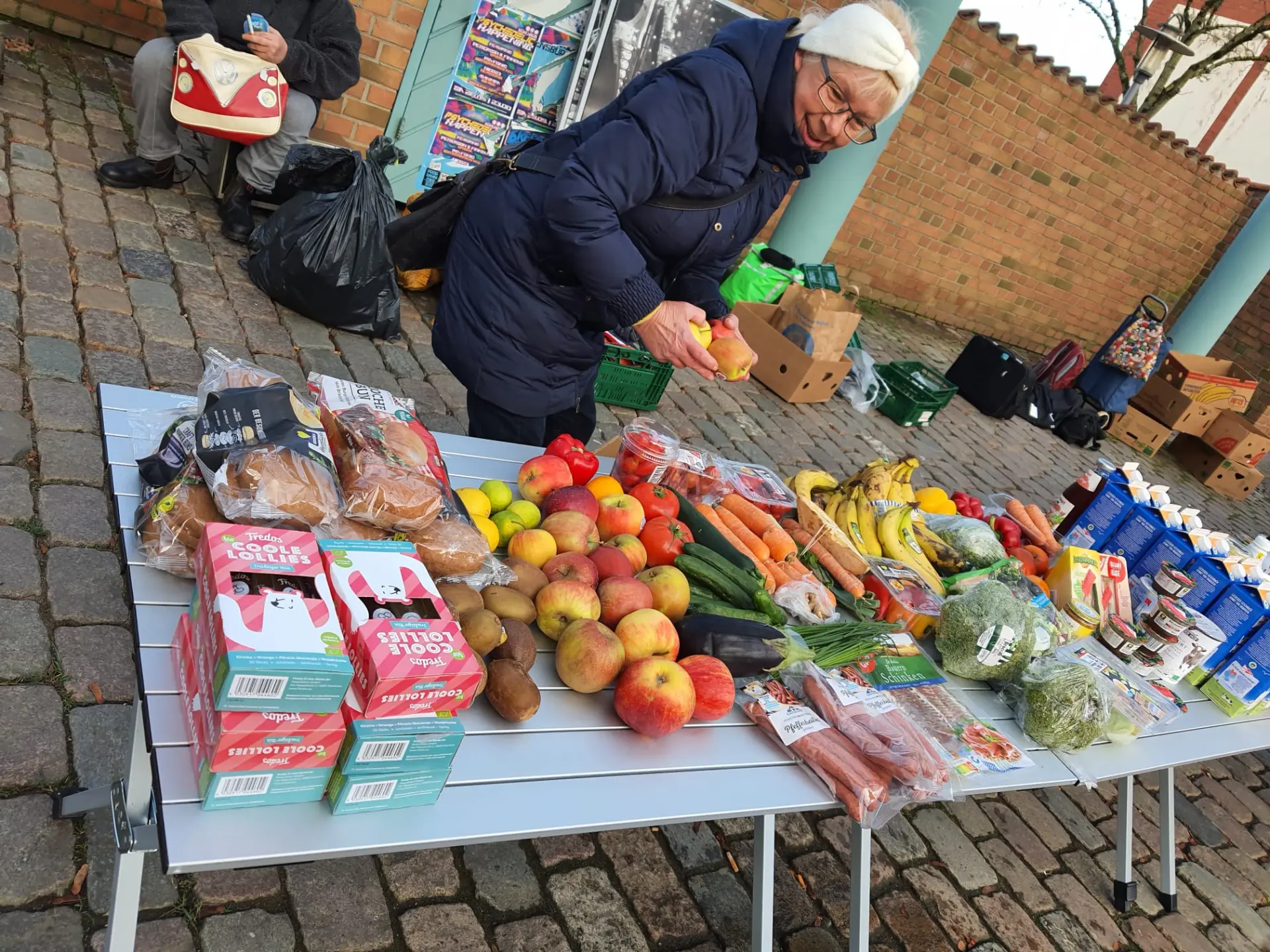 Helferin sortiert Obst und Gemüse auf dem Ausgabetisch