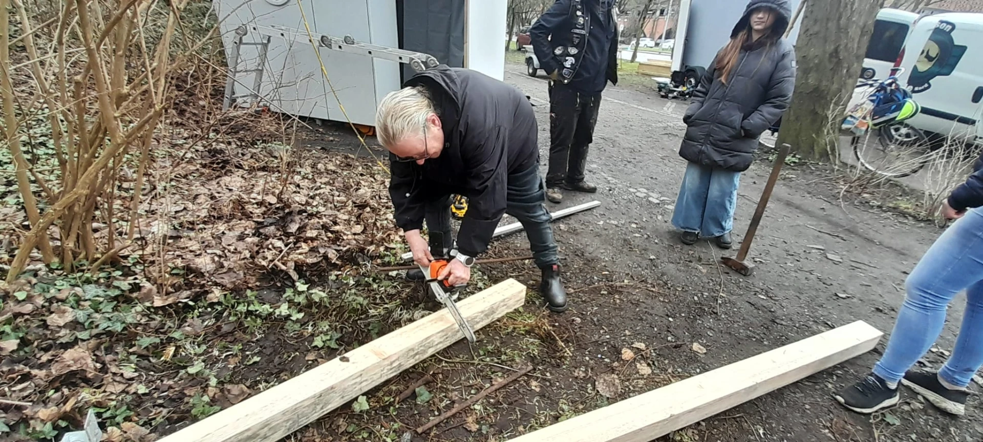 Helferin sägt mit einer Handsäge einen Holzbalken zurecht