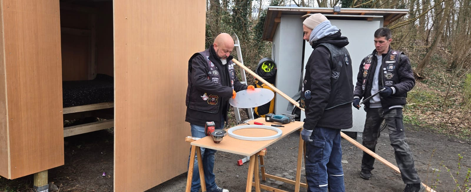 Helfer arbeiten an einem runden Fenster für die Hütte