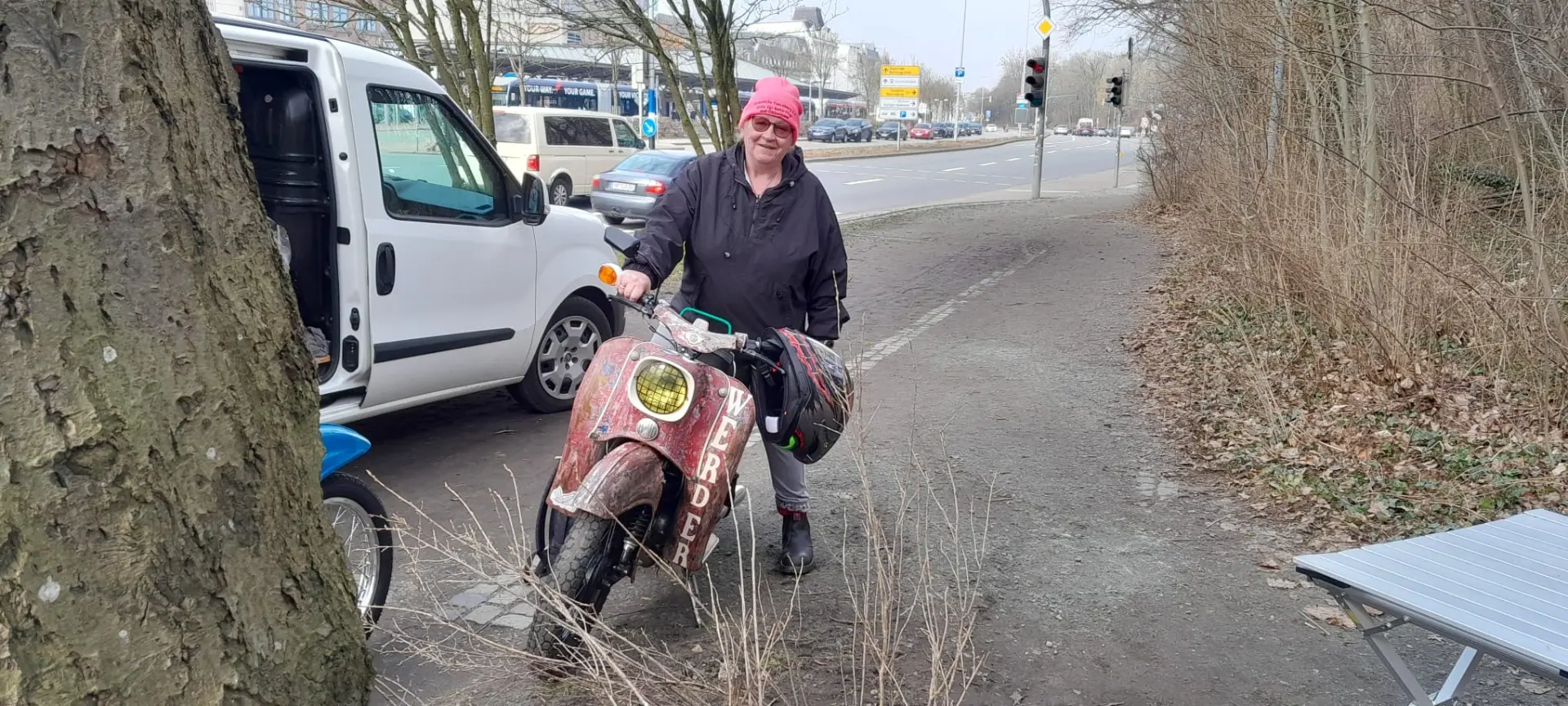 Helferin mit Moped und Transporter am Straßenrand
